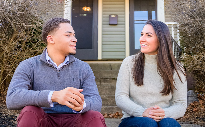 man and woman talking on the front steps of a house